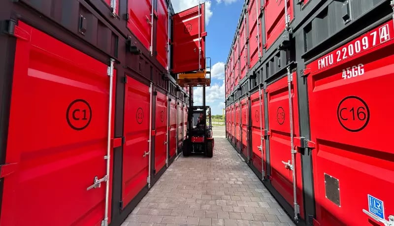 Forklift navigating between FOREMOST self storage shipping containers on-site.