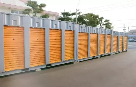 Row of bright orange 40ft self storage containers with roll-up doors, lined up in a parking lot for easy access storage.